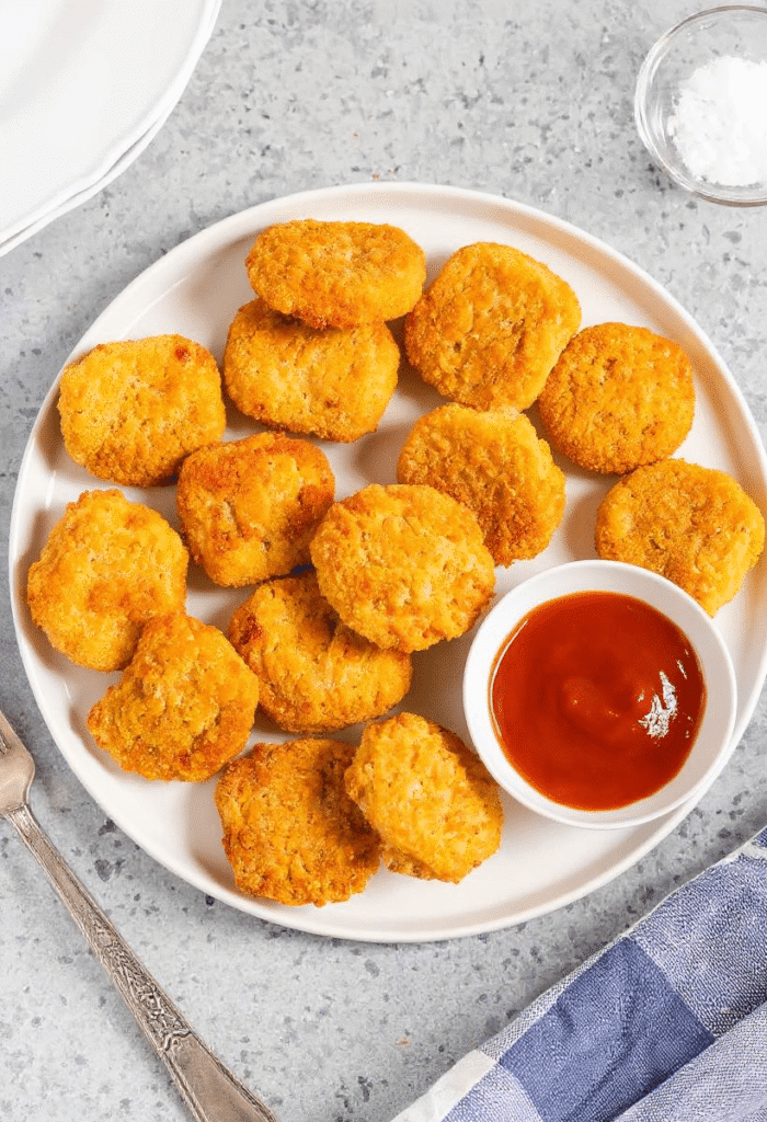 Crispy frozen chicken nuggets served on a white plate with ketchup