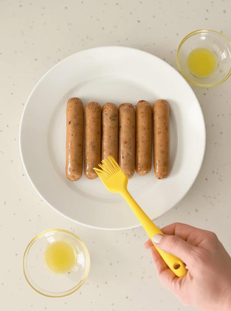 brushing raw chicken sausages with olive oil