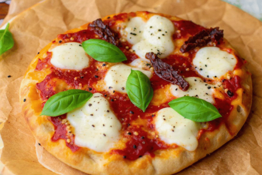 Mini Naan Air Fryer Pizza topped with melted mozzarella, sun-dried tomatoes, and fresh basil leaves.