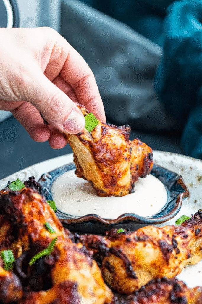 Hand dipping a crispy Ranch Air Fryer Chicken Wings into creamy ranch dressing