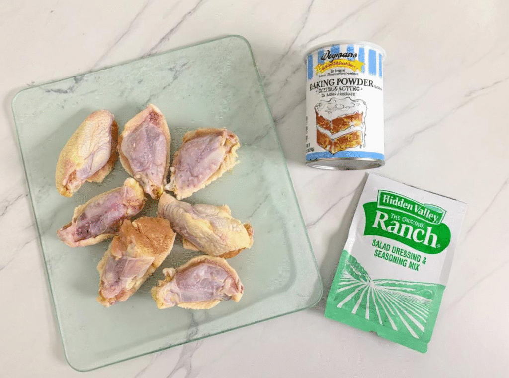 Raw chicken wings on a plate with oil, spices, and ranch dip packet