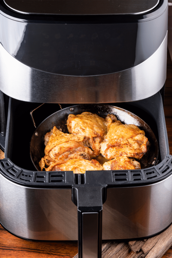 Air fryer basket with roasted chicken thighs inside , see our air fryer buying guide