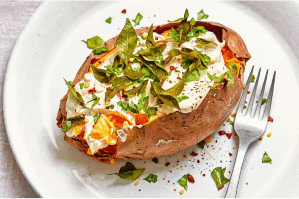 Air-fried sweet potato topped with tahini yogurt, herbs, and spices on a white plate.