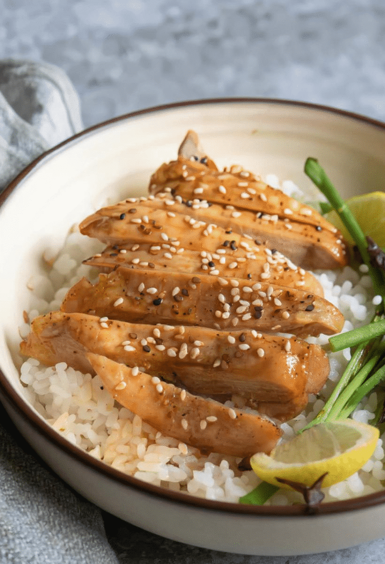 Sliced teriyaki chicken on rice with sesame seeds and lemon